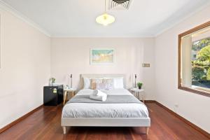 a white bedroom with a bed and a window at Queen Room in Gordon near Train & Bus Sleep 2 in Pymble
