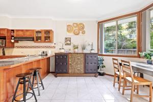 a kitchen with wooden cabinets and a table and chairs at Queen Room in Gordon near Train & Bus Sleep 2 in Pymble