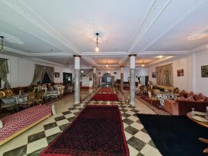 a lobby with tables and chairs and rugs at Hôtel et Restaurant ARIJ in Midelt