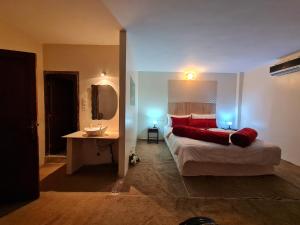 1 dormitorio con cama con almohadas rojas y lavamanos en Hôtel et Restaurant ARIJ en Midelt