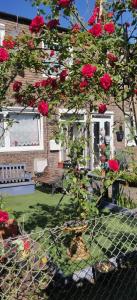 une maison avec un arbre aux roses rouges et une clôture dans l'établissement Richmond London 2 bed room Appartement, à Londres