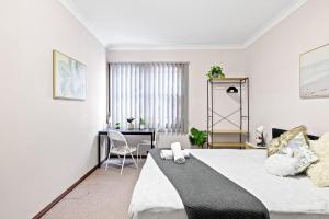 a bedroom with a large bed and a desk at King-size Bedroom in Gordon near Train & Bus in Pymble