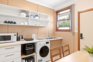 a kitchen with a washer and a microwave and a table at Double Room in Gordon near Train & Bus - 1 person in Pymble