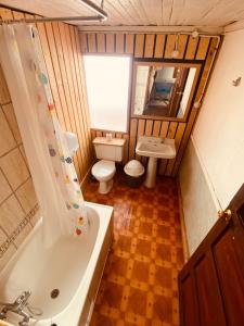 y baño con bañera, aseo y lavamanos. en HOSTAL MIRAFLORES, en Puerto Natales