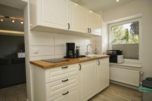 a kitchen with white cabinets and a sink and a window at Ruhig und idyllische Lage, strandnah, gratis Nutzung vom AHOI Erlebnisbad und Sauna in Sellin - Gutshaus Silvitz FeWo 02 in Bergen auf Rügen