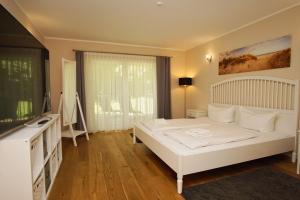 a bedroom with a white bed and a large window at Ruhig und idyllische Lage, strandnah, gratis Nutzung vom AHOI Erlebnisbad und Sauna in Sellin - Gutshaus Silvitz FeWo 02 in Bergen auf Rügen +27 photos