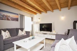 a living room with a couch and a tv at Ruhig und idyllische Lage, strandnah, gratis Nutzung vom AHOI Erlebnisbad und Sauna in Sellin- Gutshaus Silvitz FeWo 04 in Bergen auf Rügen