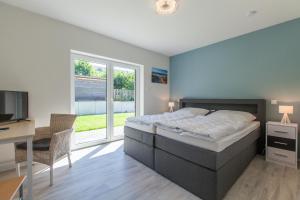 ein Schlafzimmer mit einem Bett, einem Schreibtisch und einem Fernseher in der Unterkunft Moin Moin in Nieby