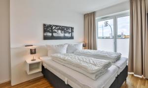 een witte slaapkamer met twee bedden en een raam bij Küstennebel - D2 in Kappeln