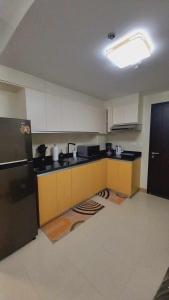 cocina con armarios blancos y nevera negra en 1BR with extra room at One Regis- Megaworld, en Bacolod