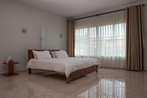 a bedroom with a bed and a large window at The Pearl Cottages in Kampala