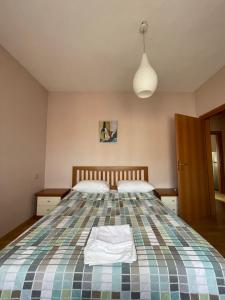 1 dormitorio con 1 cama grande con colcha a cuadros en Easy Peasy - 9th floor view downtown en Tirana