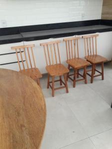3 chaises en bois et une table dans une pièce dans l'établissement Casa de Temporada Terra Caída, à Indiaroba