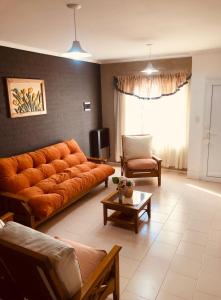 a living room with an orange couch and a table at Duplex Barrio Sur in Puerto Madryn