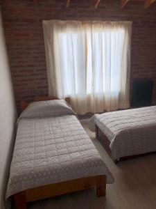 two beds in a room with a window at Duplex Barrio Sur in Puerto Madryn