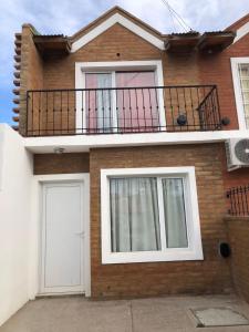 a brick house with a balcony and a white door at Duplex Barrio Sur in Puerto Madryn