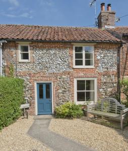a brick house with a blue door and a bench at Japonica Cottage in East Rudham