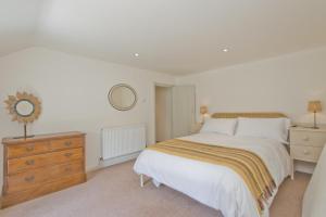 a bedroom with a bed and a dresser and a mirror at Japonica Cottage in East Rudham