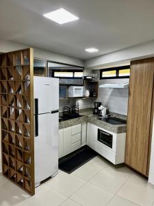 a kitchen with white appliances and a white refrigerator at Brisas de Tabatinga Flat in Conde