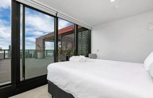 una camera con un letto bianco e una grande finestra di Magnificent Harbour View Skytower View Apartment in CBD ad Auckland