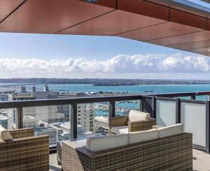 balcone con sedie in vimini e vista sull'acqua di Magnificent Harbour View Skytower View Apartment in CBD ad Auckland