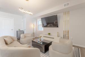 a living room with white furniture and a flat screen tv at Modern one bedroom apartment in Elizabeth