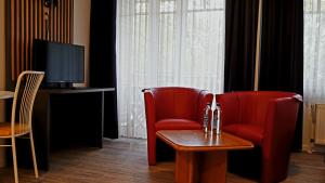 two red chairs and a table in a room with a television at Appart-Haus Business Apartments in Lingen