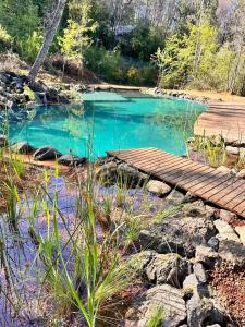 a small pond with a wooden walkway and blue water at Cabaña en el bosque-Termas de Chillán in Recinto