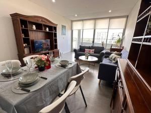 uma sala de estar com uma mesa e um sofá em Olympic park&Luxury 2b2b1p Apt pool& Free parking em Sydney