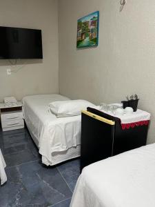 a hotel room with two beds and a flat screen tv at Pousada da Celma in Fortaleza