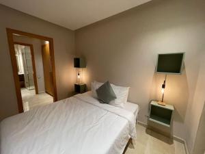 ブズニカにあるLuxury Villa Oasis, Bouznika Bayの白いベッドと薄型テレビのある寝室