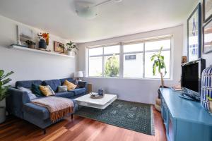 a living room with a blue couch and a tv at Vibrant Beachside Retreat - 2BR Unit in Freshwater in Freshwater