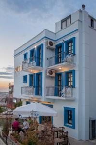 a white building with blue windows and an umbrella at Sun Hotel in Çeşme