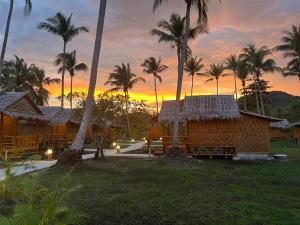 a resort with palm trees and a sunset in the background at Koh Mook Bungalows in Ko Mook