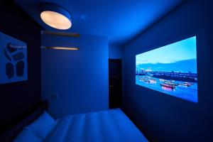 a blue room with a bed and a large tv at Grand STAY 博多駅北 in Fukuoka