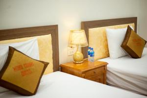 a bedroom with two beds and a lamp on a night stand at Minh Cường Guest House in Mộc Châu