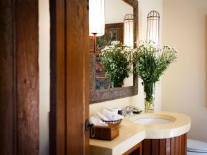La salle de bains est pourvue d'un lavabo, d'un miroir et de fleurs. dans l'établissement Villa Maridadi by Elite Havens, à Canggu