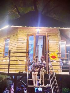 two people sitting on the stairs of a tiny house at Nhà trên cây in Hanoi