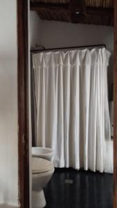 a bathroom with a toilet and a white curtain at La Calabaza Cabaña in Tilcara +94 photos