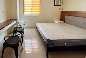 a bedroom with a bed and two chairs in it at RedDoorz @ Leoncia Apartelle Mandaue City in Mandaue City