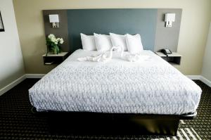 una camera da letto con un grande letto con lenzuola e cuscini bianchi di Sea Breeze Inn - San Simeon a San Simeon