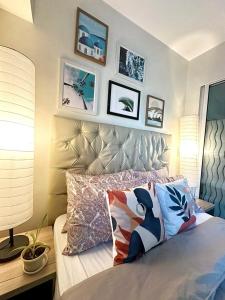 1 dormitorio con 1 cama con almohadas y cuadros en la pared en Acqua Private Residence Livingstone Tower Condo Unit with Free Wifi, en Manila
