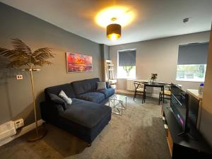 ein Wohnzimmer mit einem blauen Sofa und einem Tisch in der Unterkunft 5- Large 1 bed Apartment- West Midlands 