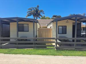 a house with a fence in front of it at Echo Beach Tourist Park in Lakes Entrance