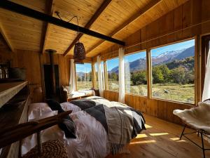 1 dormitorio con 1 cama en una habitación con ventanas en Alto Castillo, en Villa Cerro Castillo