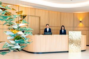 two people sitting at a reception desk with a laptop at Sole Mio Boutique Hotel and Wellness - Adults Only in Bang Tao Beach