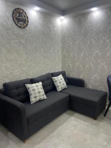 un sofá en una sala de estar con un reloj en la pared en Surami, en Surami