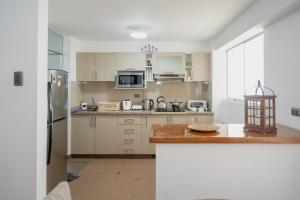eine Küche mit weißen Schränken und einer Arbeitsplatte in der Unterkunft Aura Apartamento Cusco in Cusco