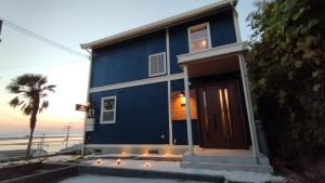 a blue house with a palm tree and the ocean at BREEZE AWAJI GOSHIKIHAMA in Tusi