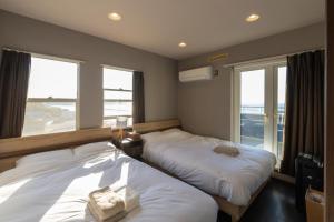 two beds in a room with two windows at BREEZE AWAJI GOSHIKIHAMA in Tusi